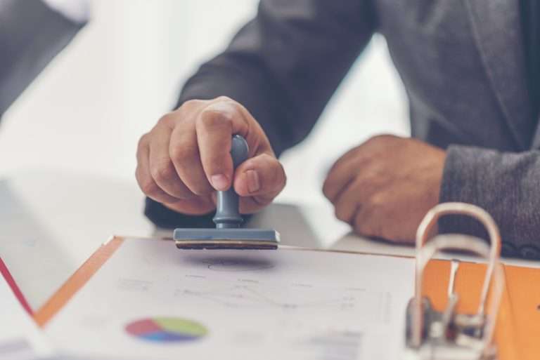 Person stamping document on desk with charts.