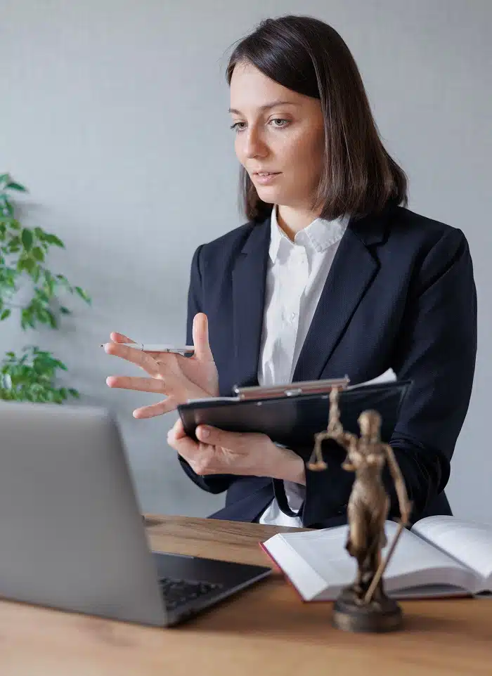 Professional woman with tablet at desk near laptop.