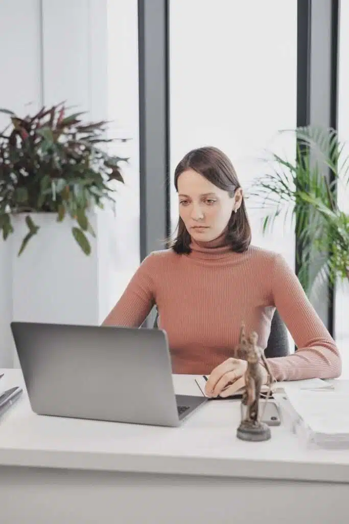 Woman working on laptop in modern office setting.