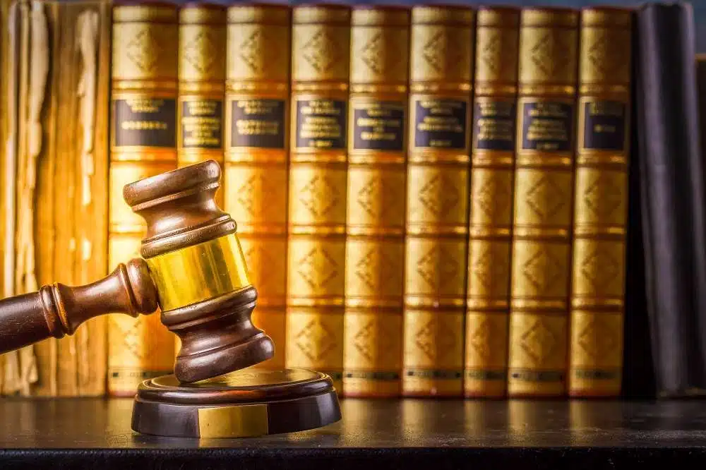 Wooden gavel in front of law books on shelf.