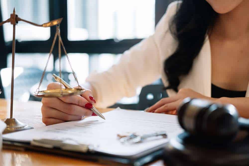 Lawyer reviews documents near Scales of Justice and gavel.