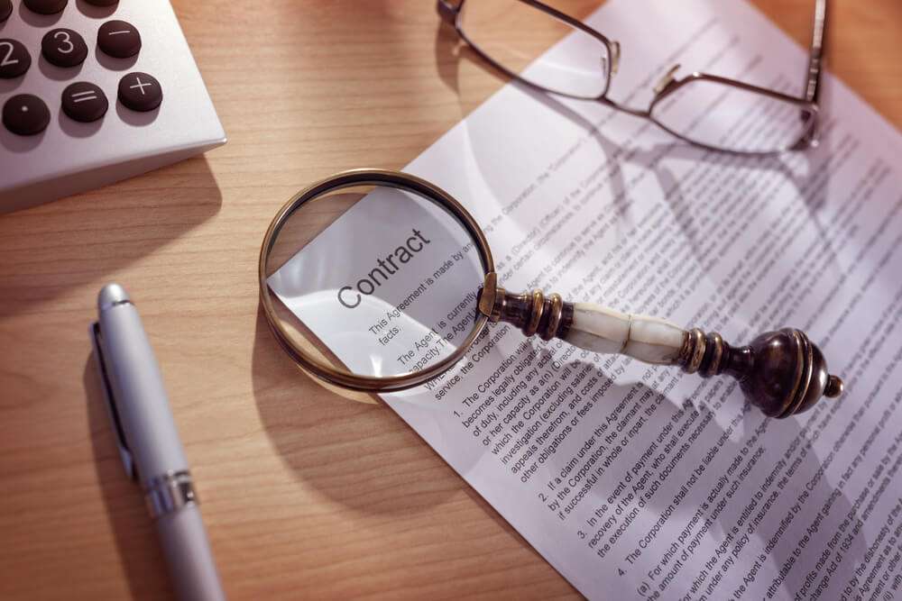 Magnifying glass inspecting legal contract document