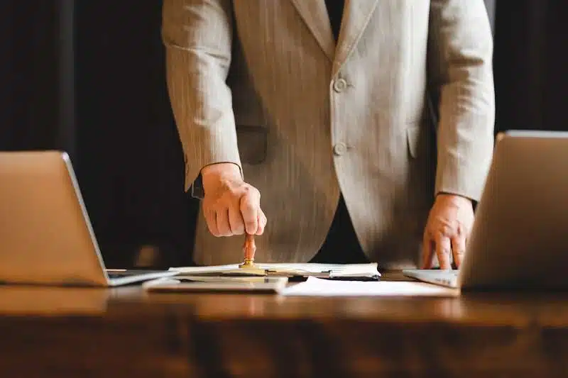 Person stamping document between laptops.