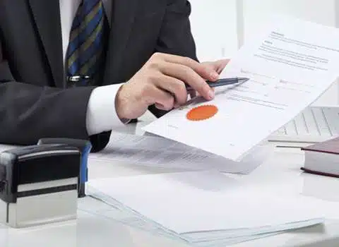 Businessman stamping document at desk.